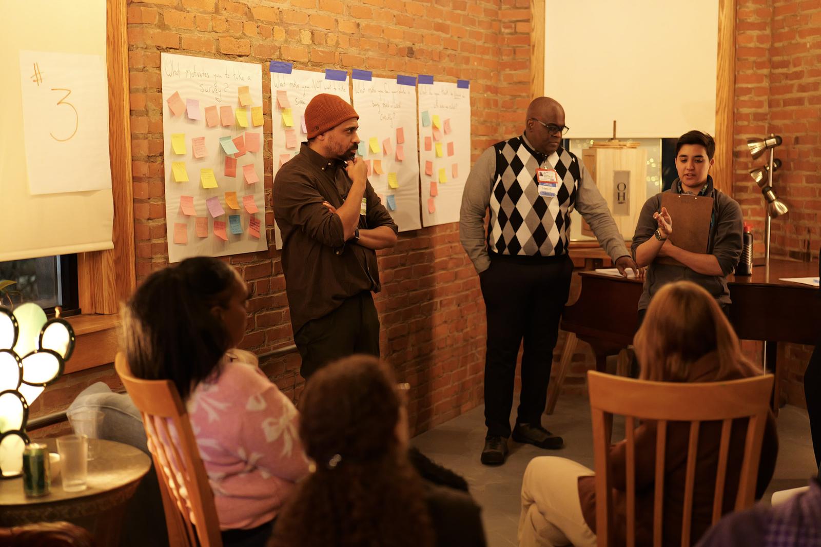 Facilitators present ideas from the sticky-note walls