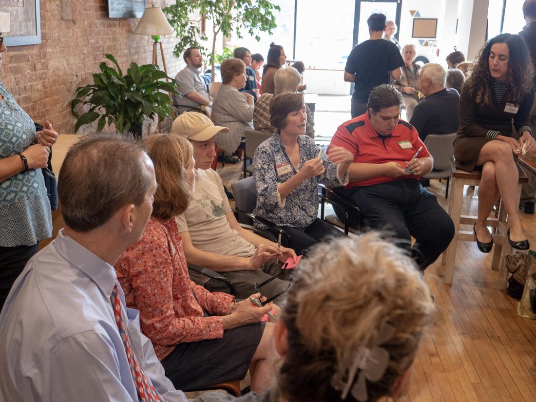 Residents seated in a large circle in a sunny coworking space